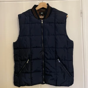 Mörkblå väst från H&M - Säljer en mörkblå väst från H&M med dragkedja framtill och två fickor med dragkedjor i strl 50.  Skriv om du har frågor!