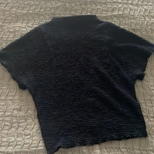 Mörkblå topp från Zara - Säljer en mörkblå topp från Zara med en unik textur. Toppen har korta ärmar och coolt mönster ,perfekt för en stilren look. Enbart använd två gånger! Tröjan är jättefin på, skriv för mer bilder! 