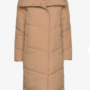Beige pufferjacka från Vila - Säljer en snygg beige pufferjacka från Vila. Jackan har knappar framtill samt en hög krage för extra värme. Perfekt för kyliga dagar. Aldrig använd och etikett är fortfarande kvar!