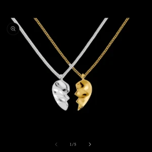 Halsband med hjärthängen i silver och guld - Två stilrena halsband med hjärthängen, ett i silver och ett i guld. Perfekt för att dela med en vän eller partner. Kedjorna är tunna och eleganta, vilket gör dem lätta att bära till olika tillfällen.