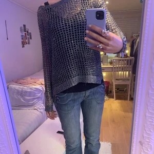 Glittrig grå stickad tröja - Glittrig grå tröja från Vero Moda med långärmad design. Perfekt för att lägga till lite glitter i din outfit (speciellt till nyår!!!). Tröjan har en lös passform och är tillverkad i ett syntetmaterial som ger en skimrande effekt.