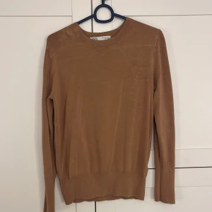 Beige tröja från Zara - Säljer en beige tröja från Zara. På bilden ser det ut som ett vitt streck långt upp på tröjan, det går bort i tvätten!!