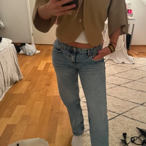 Lågmidjade Gina jeans 38 - Säljer ett par ljusblå jeans med en avslappnad passform. De har en klassisk femficksdesign och knappgylf. Perfekta för en casual look.