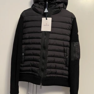 Moncler Cardigan, Storlek XL (Passar Bättre Som L) NYSKICK - En svart moncler cardigan i storlek XL, men jackan passar bättre som en L på grund av passformen. Jackan är i perfekt nyskick, jackan har aldrig använts. Den har fungerande QR-KOD och fungerande NFC-scan. Jag är öppen för att sänka priset vid en snabb affär. Tveka inte på att höra av dig om du vill ha fler bilder eller om du har några frågor. Snabba affärer prioriteras!