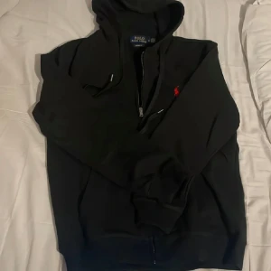 Ralph Lauren Zip Hoodie - Hej, säljer nu denna svarta zip hoodien från Ralph Lauren. Tvättad ett par gånger så färg och material fortfarande i toppskick. Luvan har krympt lite men annars helt i nyskick! Hör gärna av er vid frågor!😃