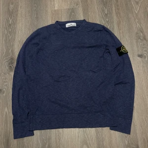 Blå tröja från Stone Island - Säljer en snygg blå tröja från Stone Island med deras ikoniska märke på ärmen.  tröjan är i exemplariskt skick och har inga tecken på användning. Storlek:M.                                 Nypris:2500kr ungefär. Mitt pris: 929kr.       Hör av er vid minsta fundering 😊