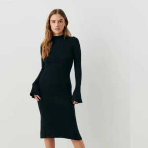 Svart ribbad klänning - Snygg svart ribbad klänning med lång ärm och figurnära passform. Perfekt för en stilren look.