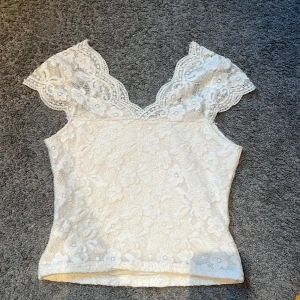 Vit spets top - Säljer den här vita spetstopen då den är för liten. Jag har använt tröjan men den är fortfarande i skick. Älskar den här tröjan, går att ha båda vid festligare tillfällen men också i t.ex skolan. 
