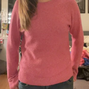 Rosa tröja från Vero Moda - Säljer en mysig rosa tröja från Vero Moda. Tröjan har långa ärmar och en rund halsringning, perfekt för kyligare dagar. Den är tillverkad i ett mjukt material som känns skönt mot huden. Storlek M