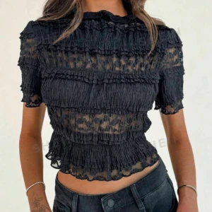 Svart kortärmad blus med volangdetaljer - Trendig svart blus med korta ärmar och volangdetaljer. Blusen har en genombruten design som ger en elegant look. Storlek m men liten i storleken💓💓 Aldrig använd! Skriv för egna bilder!