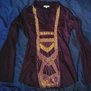 Skön mörklila tröja med indiskt broderi i spets - En mörklila tröja i super skönt material som är skönt att bära på sommaren. Den har ett broderi av spets i indisk stil på framsidan och är köpt på vila. Storlek small.