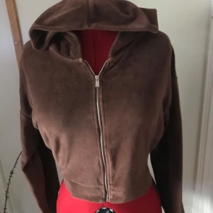 Brun croppad hoodie från Nelly - Säljer en supermjuk brun croppad hoodie från Nelly i storlek M. Den har en dragkedja framtill och en mysig huva. Perfekt för en avslappnad stil eller lager på lager under kallare dagar. Passar både till jeans och kjol!