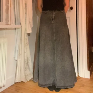 Grå lång jeanskjol  - Säljer en superfin grå långkjol i jeansmaterial från Gina tricot. Perfekt för höst och vår, den har en klassisk design med en bekväm passform. Kjolen är i mycket bra skick och passar perfekt till både vardag och fest. Den har en enkel stil som gör den lätt att matcha med olika toppar och accessoarer. Jag är 171cm för referens - Aldrig använd 