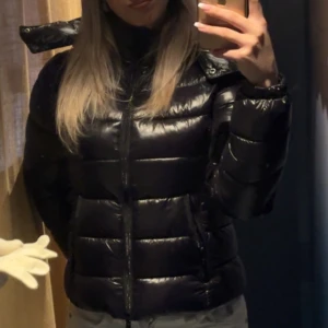Svart pufferjacka lager157 virala jackan  - Säljer en snygg svart pufferjacka i glansigt material. Jackan har en dragkedja framtill och långa ärmar. Perfekt för kyliga höst- och vinterdagar. Den är i bra skick och passar till både vardag och fest. 🖤den är från lager157 ”nikki” storlek xxs. 
