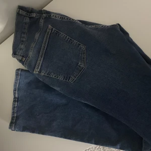 Blå jeansbyxor - Säljer ett par klassiska blå jeans i bra skick. De har en normal passform med fem fickor och knappgylf. Perfekta för vardagsbruk och kan matchas med det mesta i garderoben. Passar både till avslappnade och mer uppklädda tillfällen.