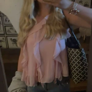 Rosa volangtopp - Säljer en superfin rosa topp med volanger. Perfekt för sommardagar eller festliga tillfällen. Toppen är ärmlös och har en luftig passform som gör den bekväm att bära. Passar perfekt med jeans eller kjol för en söt look.
