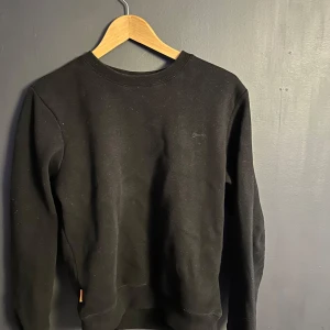 Svart tröja från Superdry - Säljer en stilren svart tröja från Superdry i bra skick. Den har en diskret broderad logga på bröstet. Perfekt för både vardag och chill. Skicket är väldigt bra 👍 