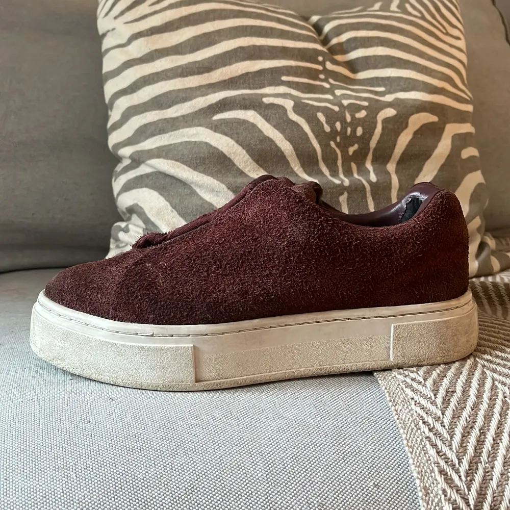 Säljer ett par snygga Eytys sneakers i mocka i färgen burgundy med en tjock vit sula. De har en stilren design utan snörning och är perfekta för både vardag och fest. Skorna är i bra skick med lite slitage på insidan. Passar perfekt till höstoutfits!. Skor.