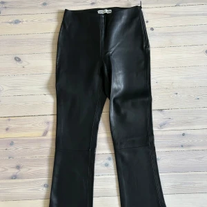 Svarta skinnbyxor från Zara - Snygga svarta skinnbyxor från Zara i storlek XS. De har en tight upp till/bootcut ner till passform och dragkedja på sidan för en stilren look. 