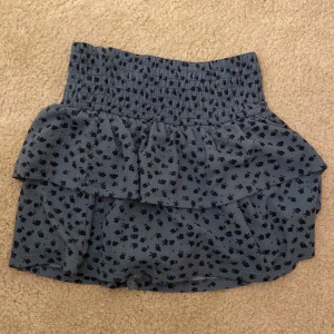 Blå blommig kjol från Zara - Söt blå kjol från Zara med små blommor och volangdetaljer. Perfekt för vår och sommar! Den har en elastisk midja för en bekväm passform. Kjolen är kort och passar bra till både vardag och festliga tillfällen. 🌸