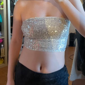 Glittrig silver/beige tubtopp - Säljer en superfin glittrig tubtopp i silver/beige. Perfekt för festliga tillfällen! Den är axelbandslös och täckt med paljetter. Toppen är i bra skick och passar perfekt till en utekväll eller nyårsfesten.🤍