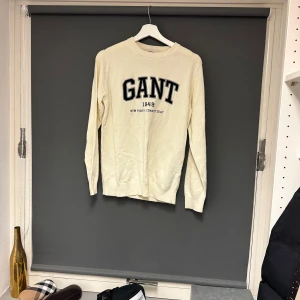 Vit långärmad tröja från GANT - Säljer en stilren vit långärmad tröja från GANT med tryck 'GANT 1949' på bröstet. Perfekt för en avslappnad men ändå snygg look. Tröjan är i bra skick och passar perfekt till både jeans och chinos. Storlek S. 
