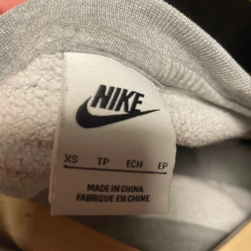 Säljer en grå sweatshirt från Nike i storlek XS. Tröjan är tillverkad av 80% bomull och 20% polyester, vilket gör den både bekväm och hållbar. Den har långa ärmar och en klassisk rund halsringning. Perfekt för höst och vår! Tröjan är i ett mycket bra skick förutom en söm som har gått upp och sytts igen på baksidan, den syns på sista bilden men märks inte när tröjan är på!. Tröjor & Koftor.