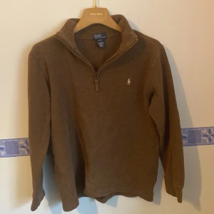  Polo Ralph Lauren half zip hood! - Säljer en snygg brun zip-up tröja från Polo Ralph Lauren.  Tröjan har en dragkedja vid halsen och är perfekt för höst och vinter. Den är i bra skick, Perfekt för en stilren och bekväm look! Passar storlek Xs/S