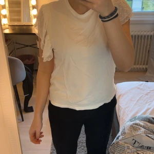 Vit topp med volangärmar från Amisu - Säljer en söt vit topp från Amisu i storlek M. Den har korta volangärmar med prickigt mönster och spetsdetaljer. Perfekt för vår och sommar! 🌸 Sitter som en strl S