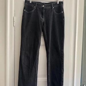 Svarta jeans med vita sömmar - Säljer ett par svarta lågmidjade jeans med vita kontrastsömmar. De har en klassisk femficksdesign och en knappgylf. Perfekta för både vardag och fest! 🖤