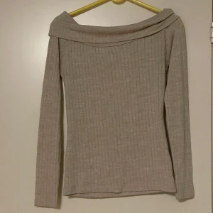 Beige Offshoulder tröja - Säljer en superfin beige ribbad tröja med offshoulder-design. Är lite nopprig men är i bra skick.