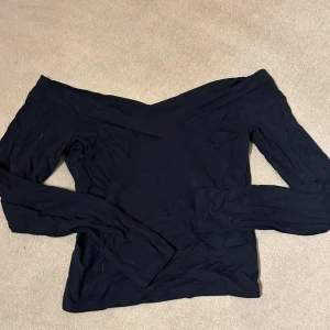Svart offshoulder topp från H&M - Snygg svart offshoulder topp från Divided i storlek S. Perfekt för en kväll ute eller en avslappnad dag. Toppen har långa ärmar och en stilren design som passar till det mesta. Ett måste i garderoben för alla som älskar stilrena plagg!