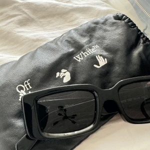 Svarta solglasögon från Off-White - Lite lösa men går nog att fixa hos optikern säljer  ett par snygga svarta solglasögon från Off-White. De har en rektangulär form och är i nyskick. Glasögonen har en cool, modern design med Off-White-loggan på sidorna. Perfekta för att ge din outfit en stilren touch!