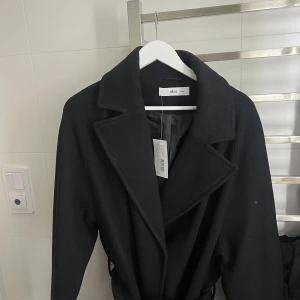 Kappa - Svårt Kappa i ullblandning med vävt, glansigt foder. Stängning med två dolda tryckknappar. Knytskärp i midjan och två fickor. Storlek 46/48🌟