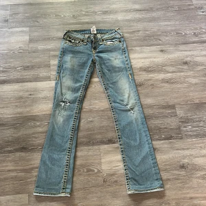 True Religion Jeans - Säljer mina True Religion Jeans i storlek 26 då dom är lite för små. Små slitningar vid knäna, se bild, annars superbra skick.Midjemått: ca 35 cm rakt över och innerbenslängden är ungefär 75 cm. Hör av er vid frågor!🙌🏻 