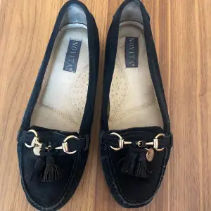 Novita Parma Loafers, svarta. Loafers i getmocka med ett dekorativt gulfärgat spänne och tofs. Skon har skinnfoder och en skön sula. Nypris: 1 300 kr