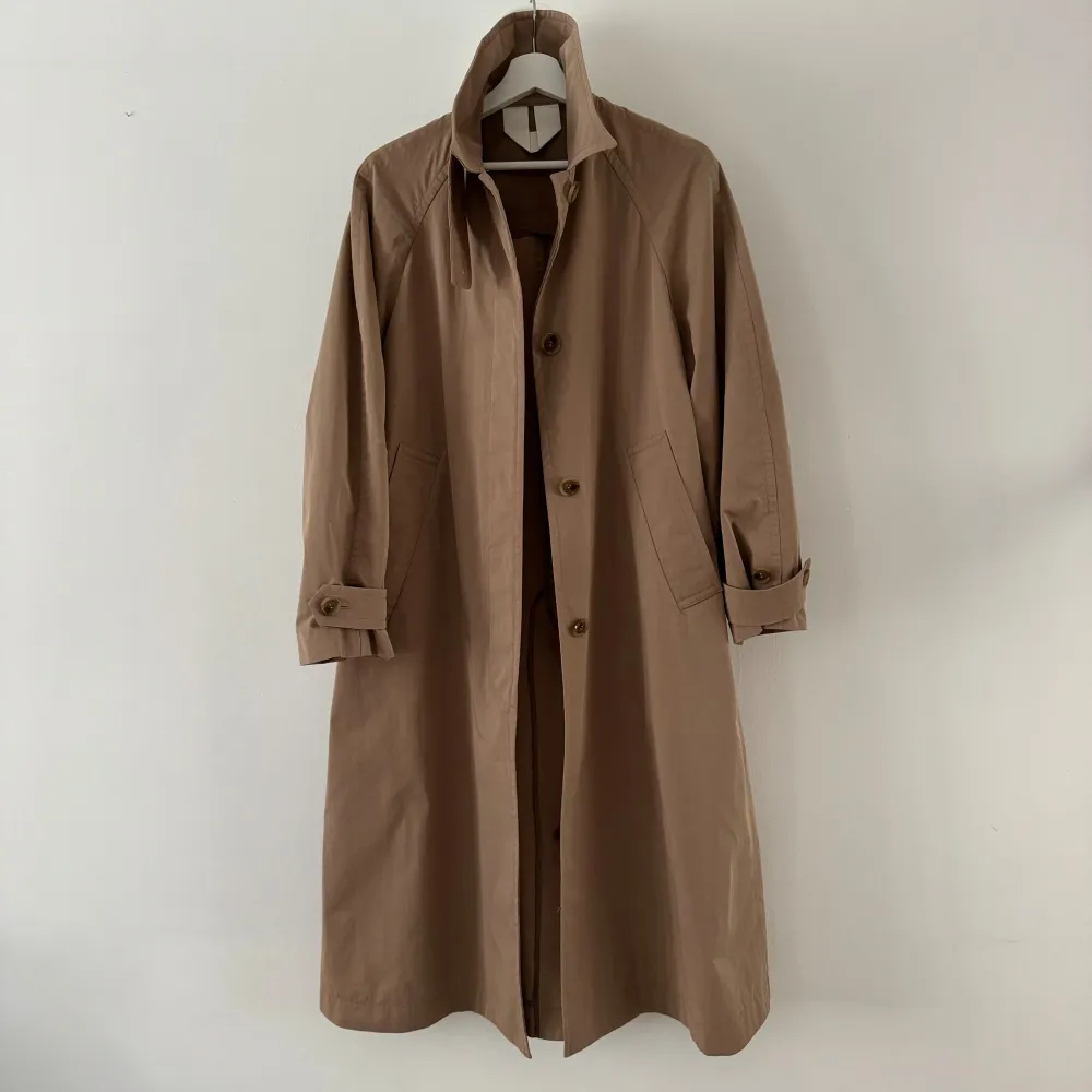 Oversized trenchcoat i en bomullsblandning. Raglanärm och dold knäppning framtill. Krage med avtagbar vindslå. Snedställda stolpfickor fram och flikar med knäppning vid ärmsluten. Sprund bak. KOMPOSITION: Bomull 72%, Polyamid 28% FODER: Viskos. Jackor.