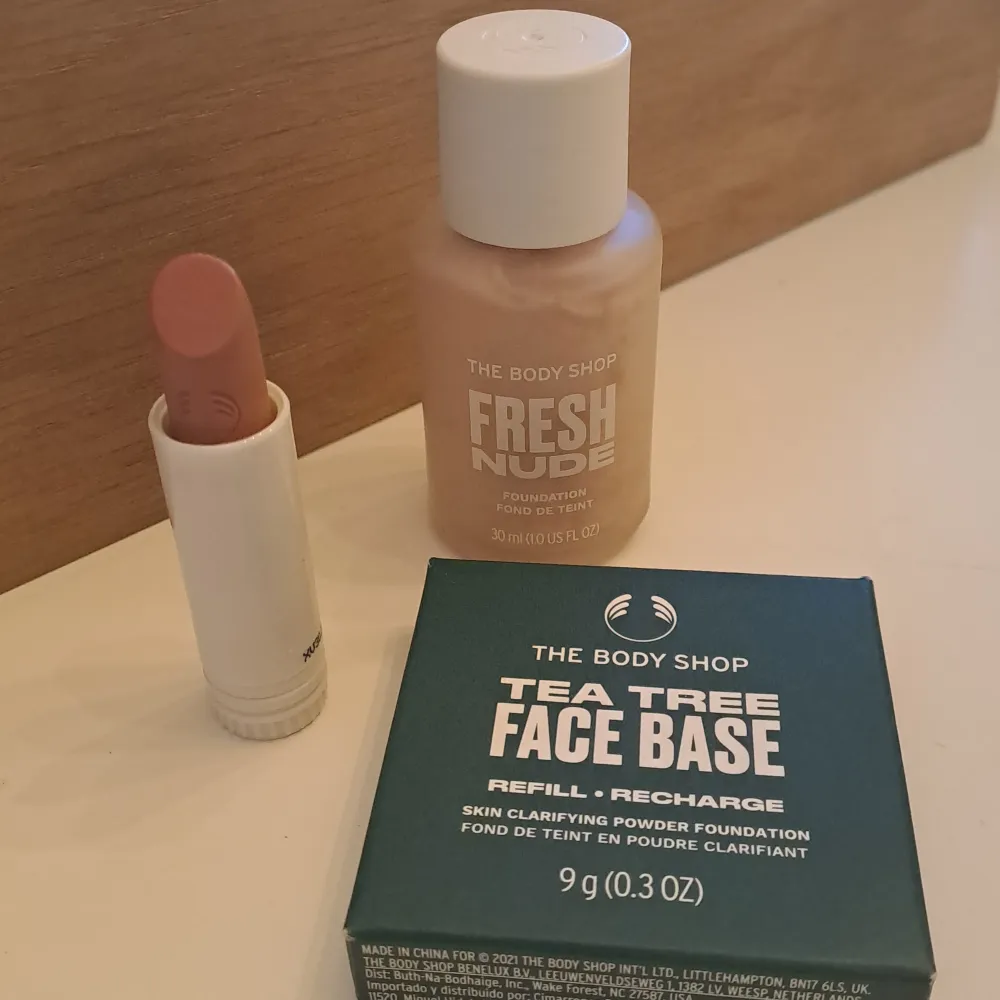 Säljer ett sminkset från The Body Shop som innehåller en Fresh Nude Foundation, en Tea Tree Face Base och ett läppstift. Foundationen är i en ljus nyans och ger en naturlig finish. Tea Tree Face Base är en puderfoundation i nyansen Light 1C, perfekt för att hålla huden matt och fräsch. Läppstiftet har en mjuk, nude färg som passar till vardags.. Skönhet.