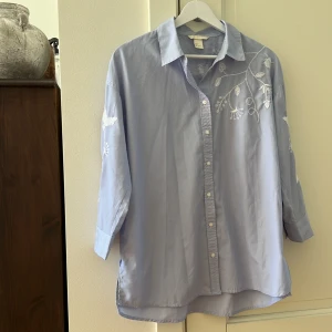 Vitblårandig skjorta med broderidetaljer - Använd fåtal gånger