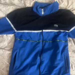 En blå Lacoste zip hoodie lite använd. Storlek 170 