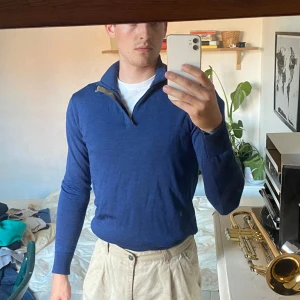 Blå tröja från Hansen & Jacob - Säljer en snygg blå ylletröja från Hansen & Jacob i storlek S. Tröjan är en half-zio har en dragkedja vid halsen och är långärmad. Perfekt för höst och vår med sin stilrena design och bekväma passform.