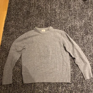 Grå tröja från H&M - Säljer en stilren grå tröja från H&M i regular fit. Tröjan är långärmad och har ribbade muddar vid ärmslut och nederkant. Perfekt för en avslappnad look.