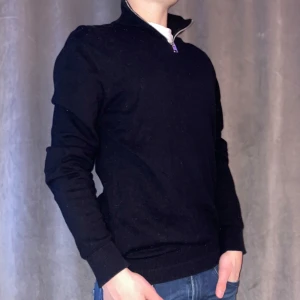 Svart tröja med dragkedja från Jack & Jones - Snygg svart tröja från Jack & Jones med dragkedja vid halsen. Perfekt för en stilren look, oavsett om du är på språng eller bara vill hålla det enkelt. Passar bra till jeans eller chinos.