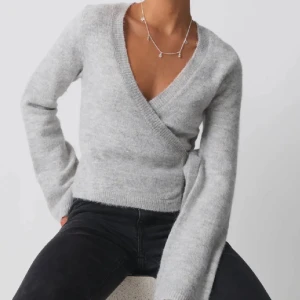 Grå omlottstickad tröja - Säljer den populära Gina Tricot knytkoftan i storlek S. Köpte två likadana av misstag, så denna är helt oanvänd och kommer med originalförpackning och prislapp kvar. Koftan har aldrig tagits ur paketet, så jag har tyvärr inga bilder på den använd.