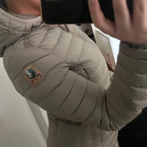 Beige dunjacka från Parajumpers - Säljer min parajumper irene jacket. Storlek XS. Har ett lagat hål och ett litet bränt hål (se sista bilden) 