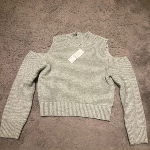 Grön  stickad tröja från Gina tricot  - Säljer en stilren ljus grön  stickad tröja från Gina  med offshoulder-design. Tröjan har långa ärmar och ribbade kanter, perfekt för kyligare dagar. Ny med tag kvar!