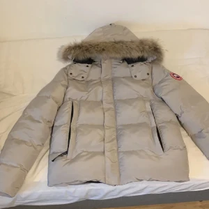 Beige dunjacka från Canada Goose - Säljer en beige dunjacka från Canada Goose med pälskantad huva och dragkedja. Storlek M men det stå xl. Jackan är helt ny. 