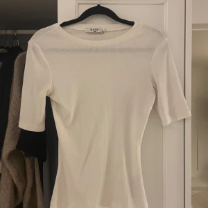 Vit ribbad topp från NA-KD - Säljer en vit ribbad topp från NAKD. Tight passform och trekvartsärmar. Toppen är stor i storleken, är vanligtvis en Xs-s men denna passar ändå mig. 