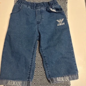Blå jeansshorts från Armani - Snygga blå jeansshorts från Armani med elastisk midja och logotypdetaljer på framsidan och fållen. Perfekta för en avslappnad stil med två bakfickor för extra funktionalitet.