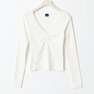 Vit långärmad topp  - Säljer en stilren vit långärmad topp från Gina med v-ringning och rynkdetalj framtill. Perfekt för en chic och enkel look.